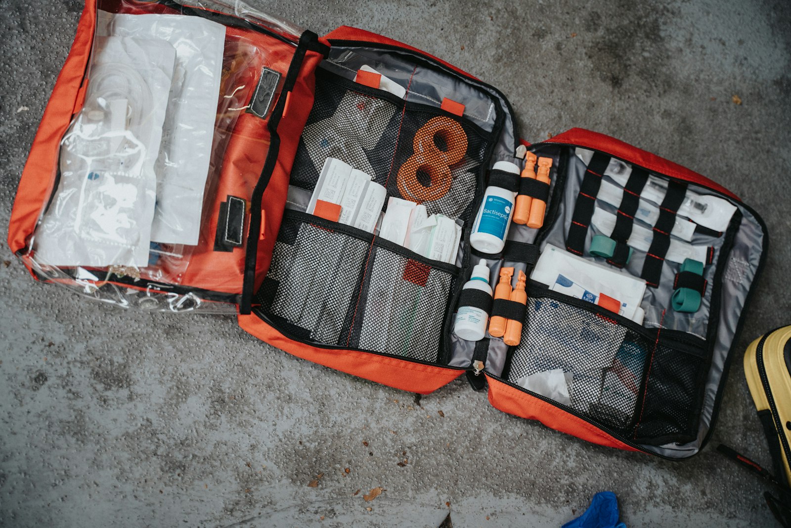 Bolsa botiquín roja abierta con vendas y material sanitario sobre una superficie gris