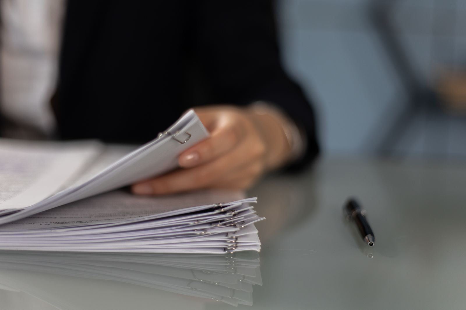 Persona ordenando un montón de documentos sobre un escritorio