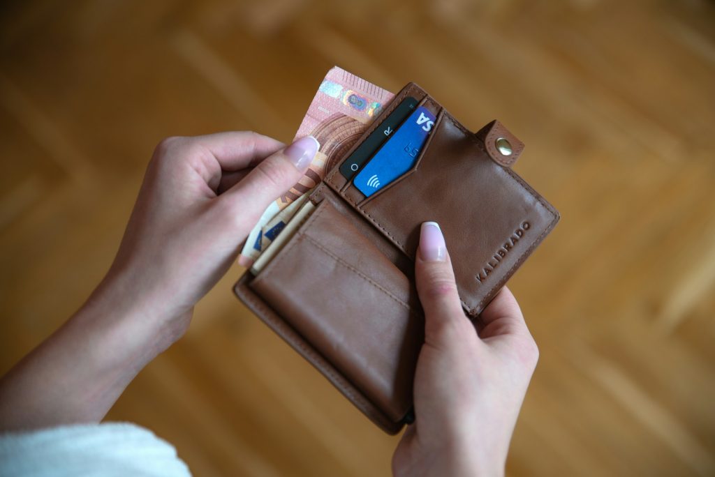 Una persona sostiene un tarjetero de piel marrón con tarjetas en su interior