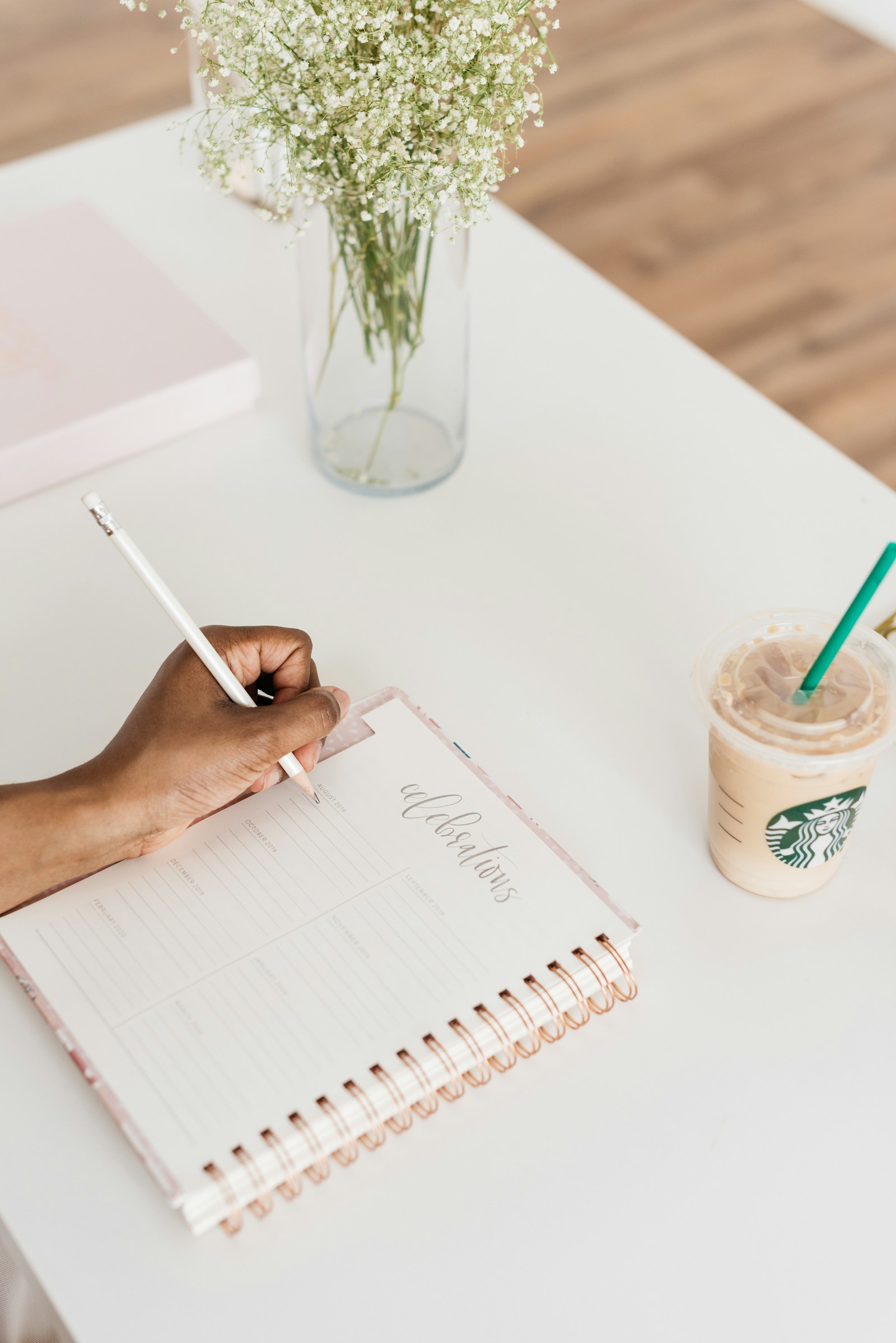 Persona escribiendo en un cuaderno sobre un escritorio con una taza de café